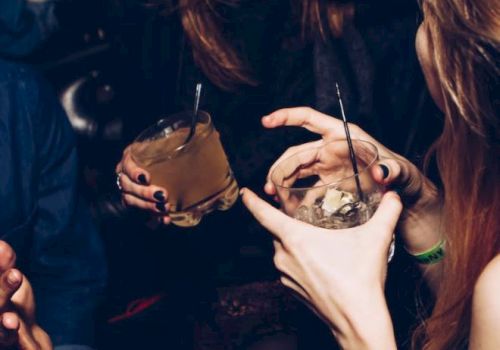People are enjoying a social gathering with drinks in their hands, laughing and having a good time.
