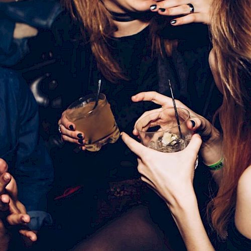 People are enjoying a social gathering with drinks in their hands, laughing and having a good time.