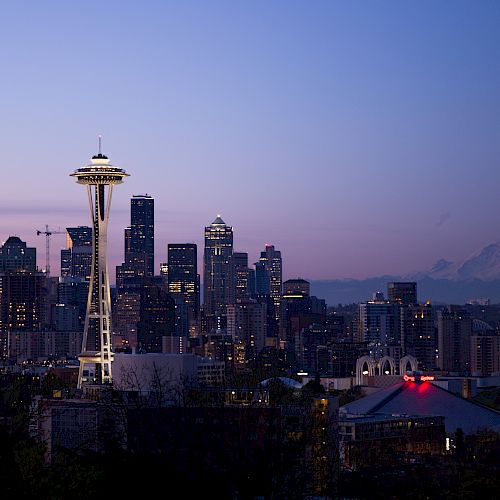 This image shows the Seattle skyline at dusk, with the Space Needle prominently featured and Mount Rainier visible in the background.